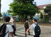 Personel Sat Lantas Polres Bima Kota Bantu Anak Sekolah Menyeberang Jalan